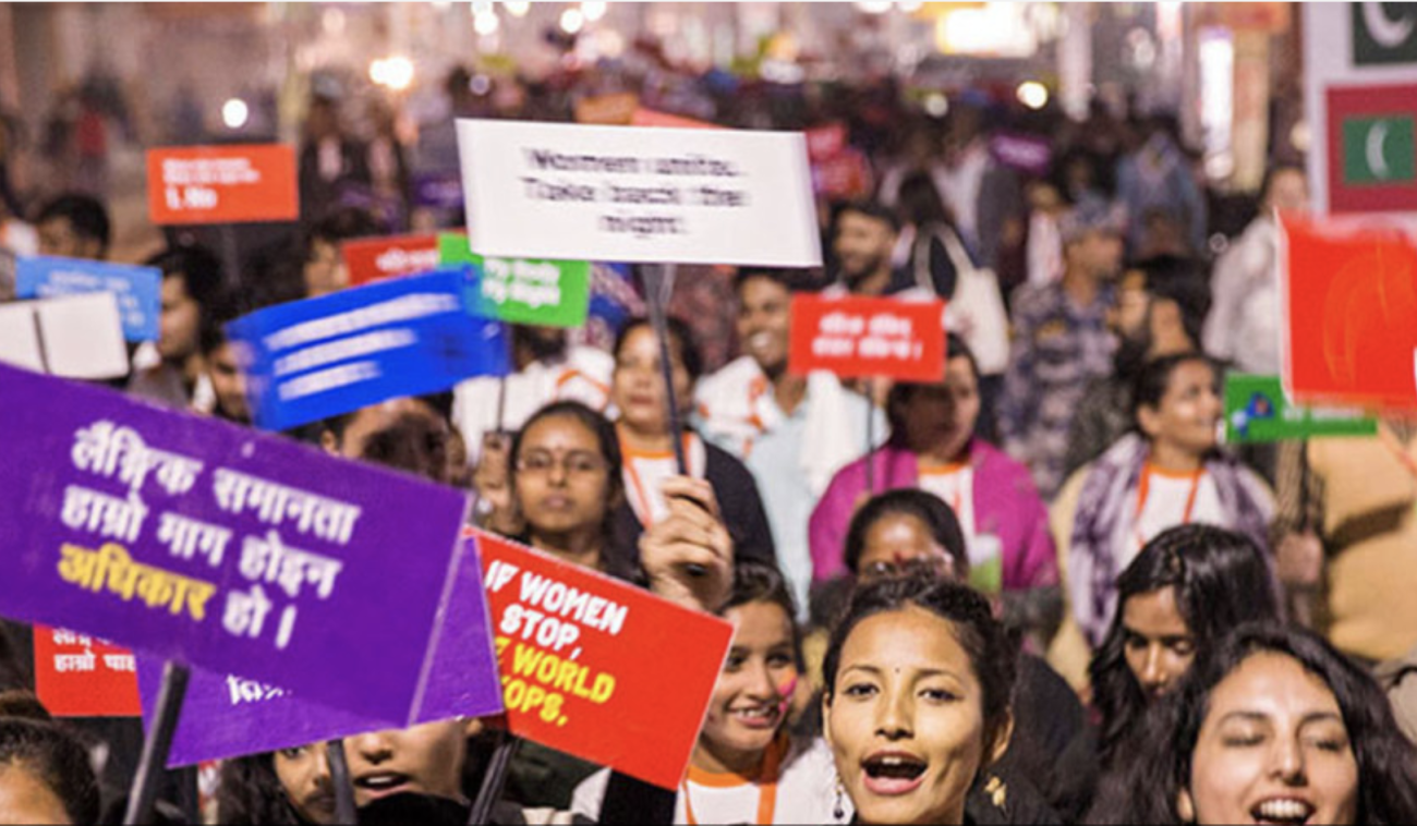 Gran cantidad de personas adultas, de todas las edades, sostienen pancartas durante una manifestación por la igualdad de género y los derechos de la mujer en Nepal.