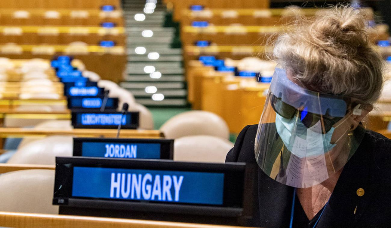 Dans une salle vide de l'Assemblée générale, Katalin Bogyay, représentante permanente de la Hongrie auprès des Nations Unies, prépare ses bulletins de vote pour les élections. Elle à la tête penchée sur son pupitre et porte une visière de protection.