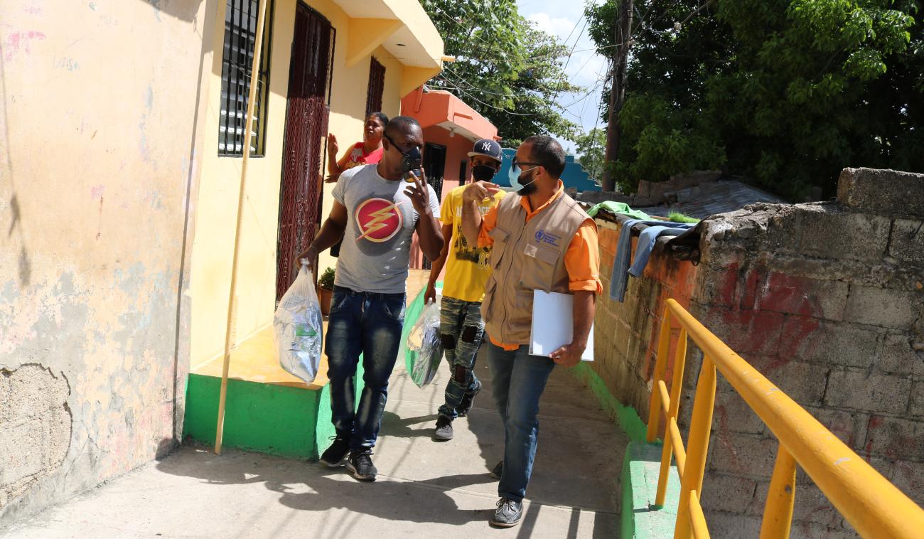 UN staff with local residents walk along homes in a neighbourhood in the Dominican Republic.