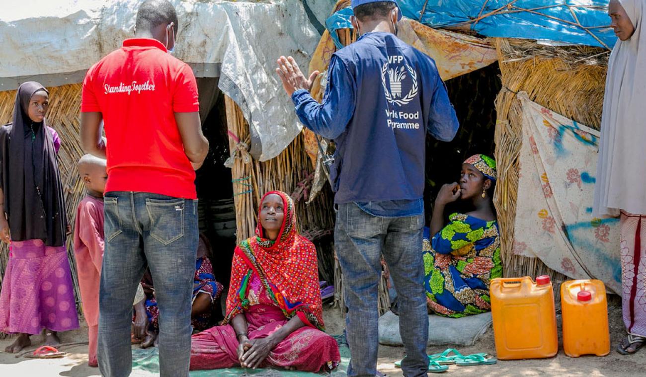 أحد موظفي برنامج الأغذية العالمي يقابل أشخاصًا نازحين في مخيم للنازحين داخليًا في مايدوجوري، نيجيريا.