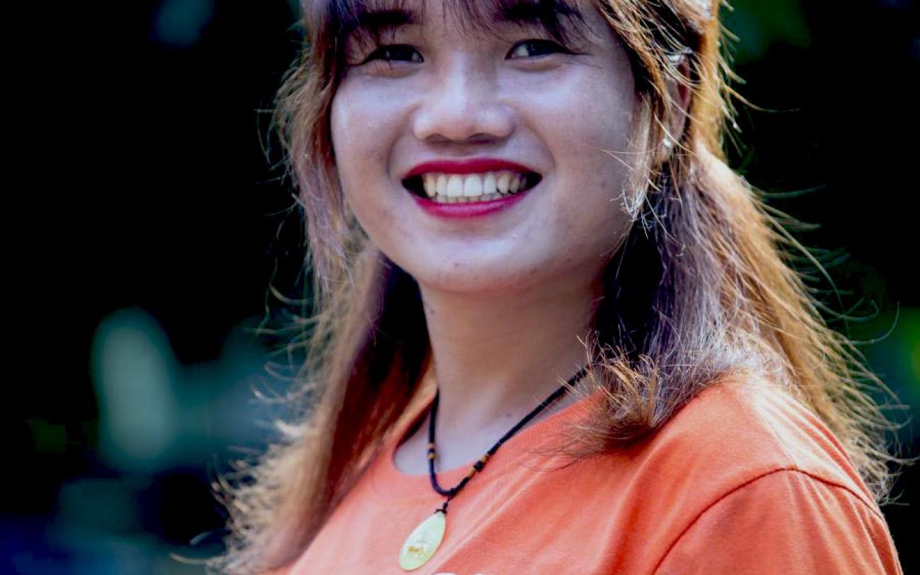 Primer plano de Kim Thuy, quien tiene una gran sonrisa en su rostro, mirando a la cámara. Kim Thuy es una activista transgénero de Vietnam que sueña con organizar un desfile del orgullo gay en la comunidad donde creció.