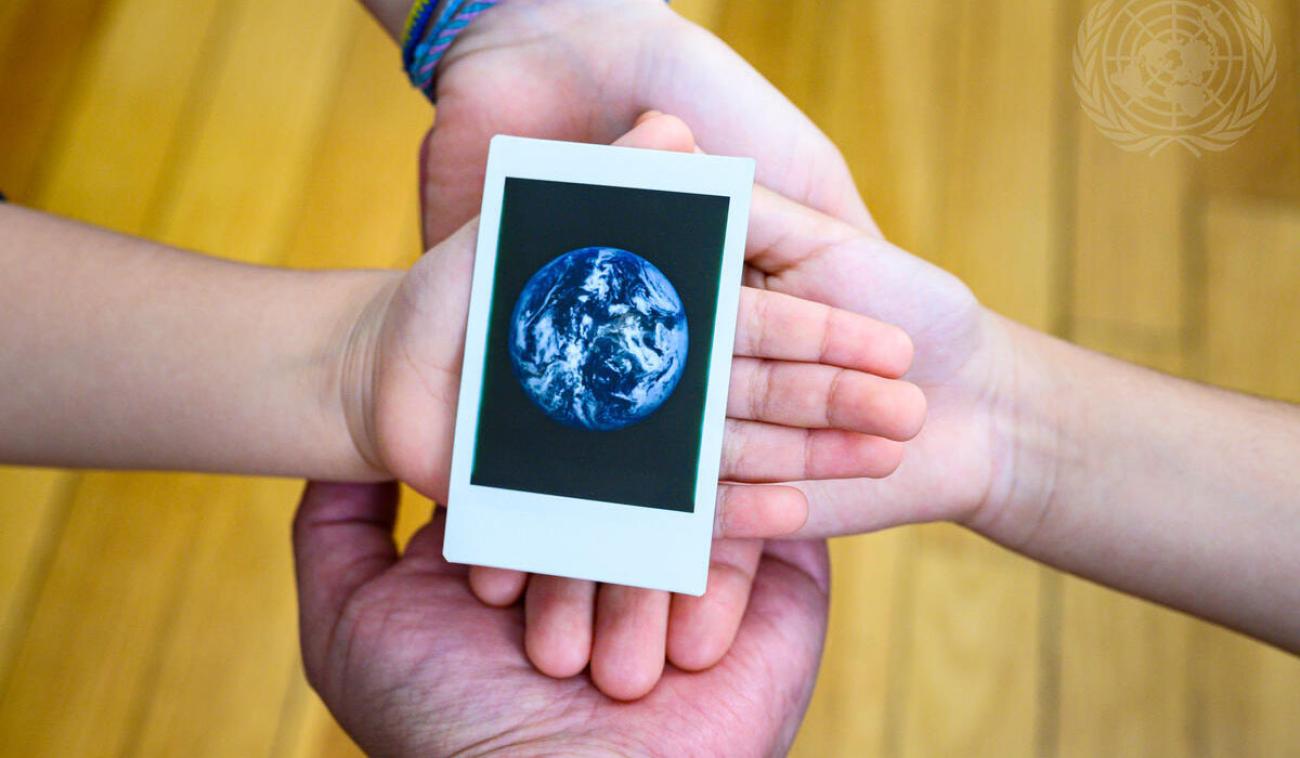 Cuatro manos sostienen una imagen de la tierra en el Día Internacional de la Madre Tierra (22 de abril).