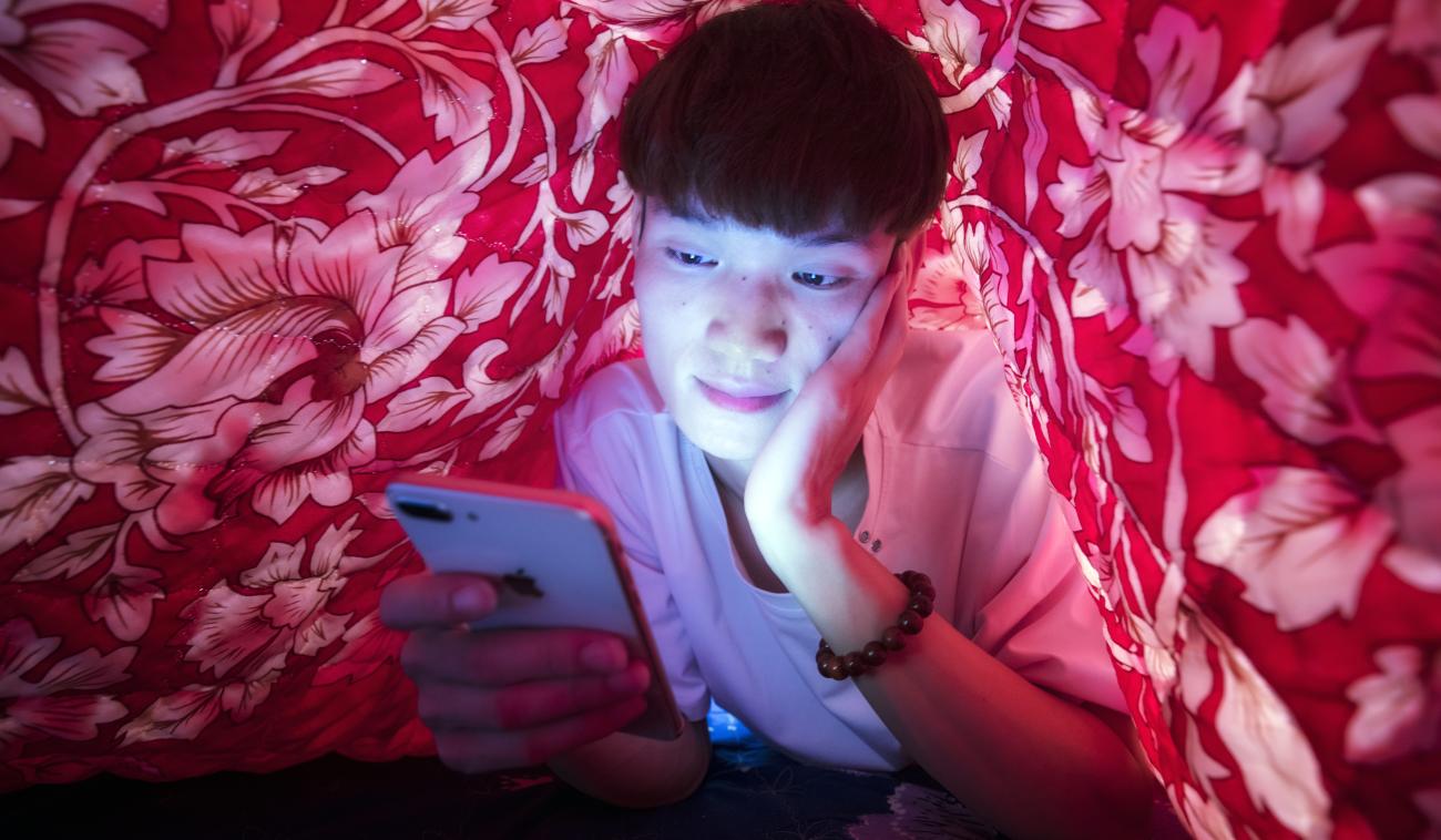 Bui Thi Chi bajo las sábanas mirando un teléfono móvil.
