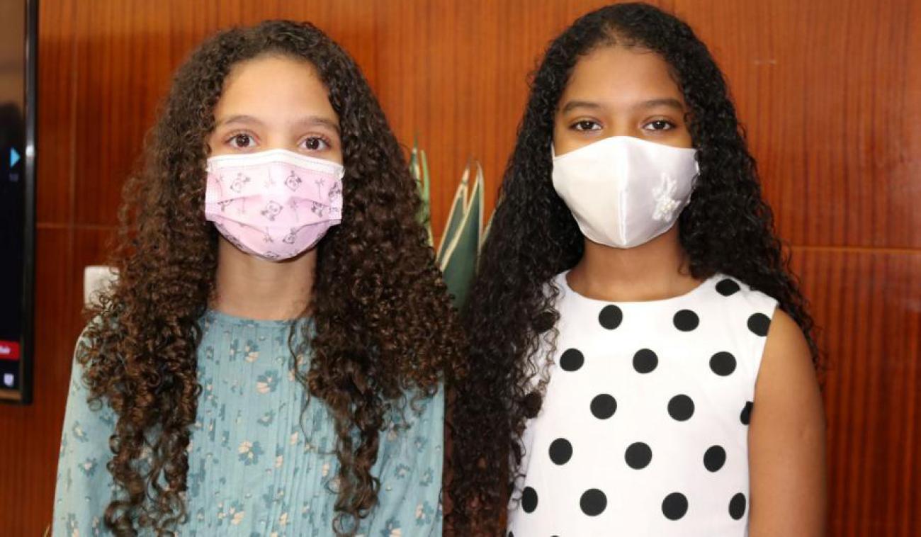 Anyah Spencer Maia and Victoria Roberts Gonçalves Gomes, age 10 stand side-by-side facing the camera wearing face masks.