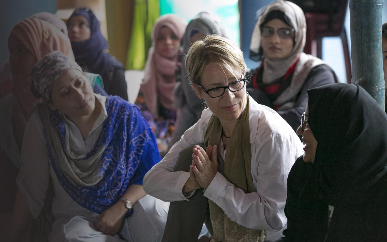 La Coordinadora Residente de las Naciones Unidas en Bangladesh se sienta con un grupo de mujeres líderes en el suelo de un centro de usos múltiples.