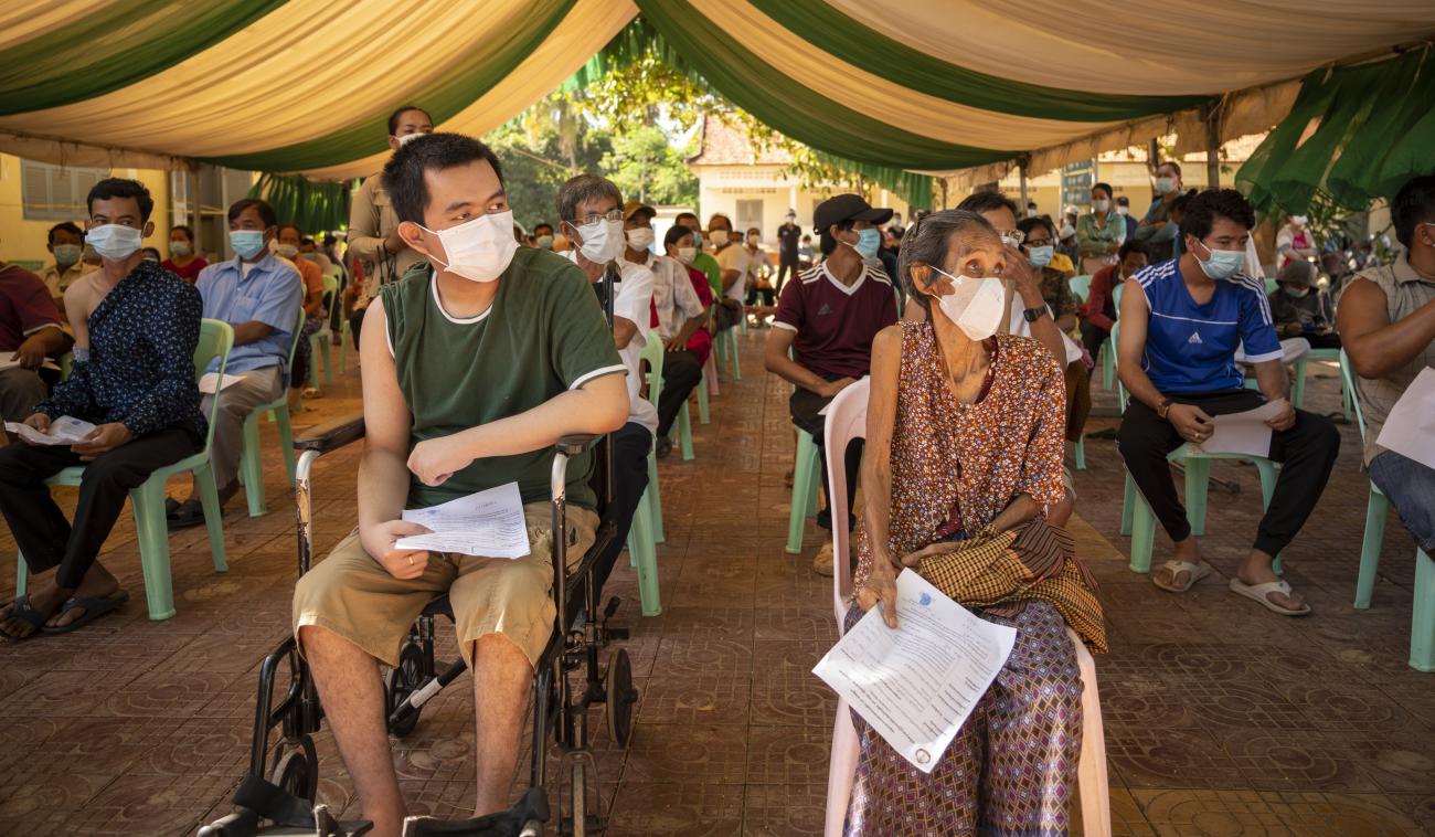 Elder and people with disabilities sit socially distanced and masked as they wait for their vaccinations.