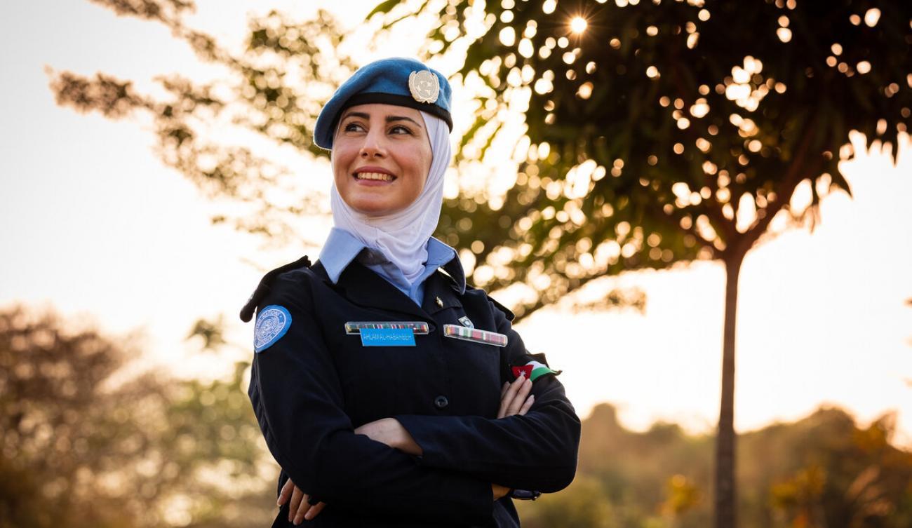 La capitana Ahlam Al-Habahbeh, orgullosa de su uniforme, posa para la cámara al aire libre junto a un árbol.
