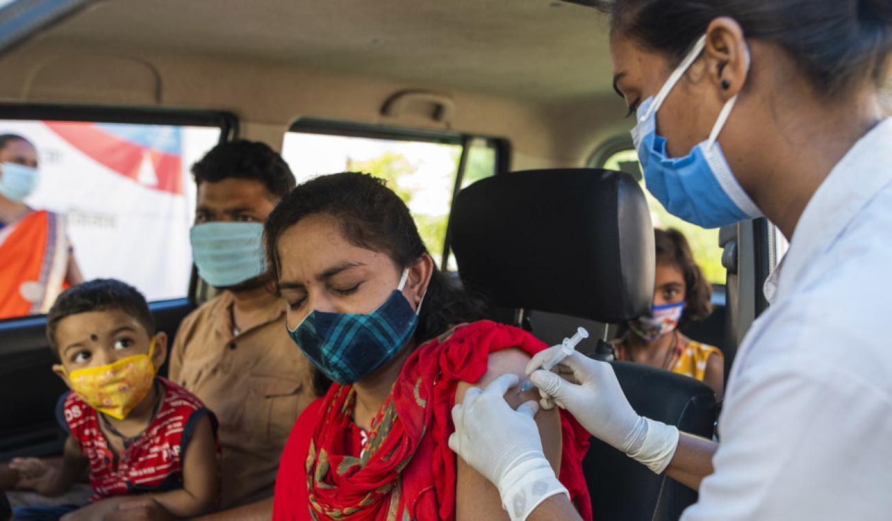 A women closes her eyes as she gets her first dose of the COVID-19 vaccination at a drive-in vaccination centre at MP Tourism Motel in Jhabua, Madhya Pradesh.