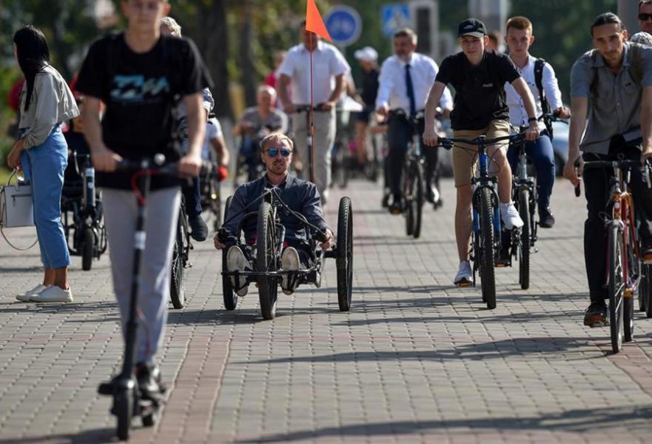 Una persona conduce una bicicleta de mano junto a personas en bicicletas y scooters. 