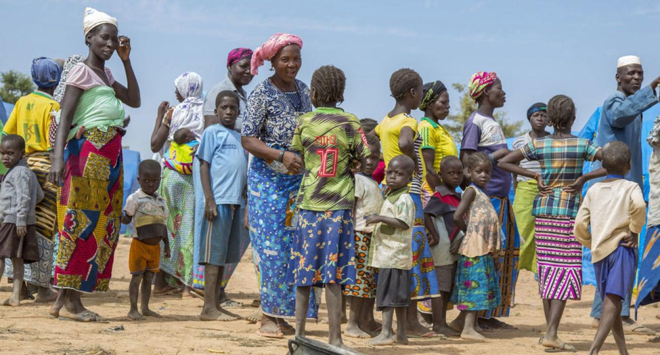 مجموعة من النساء والرجال والأطفال تتجمع في الخارج في مخيم في شمال شرق البلاد.