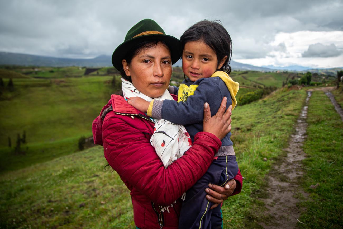 A woman holds a child in her arms on a cloudy day. 