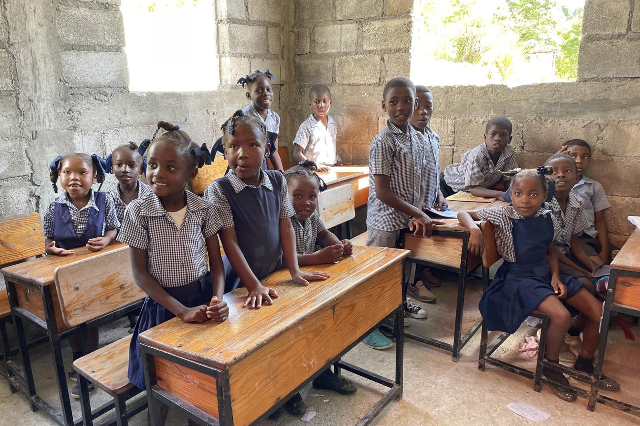 A group of school children near their desks inside a school. 