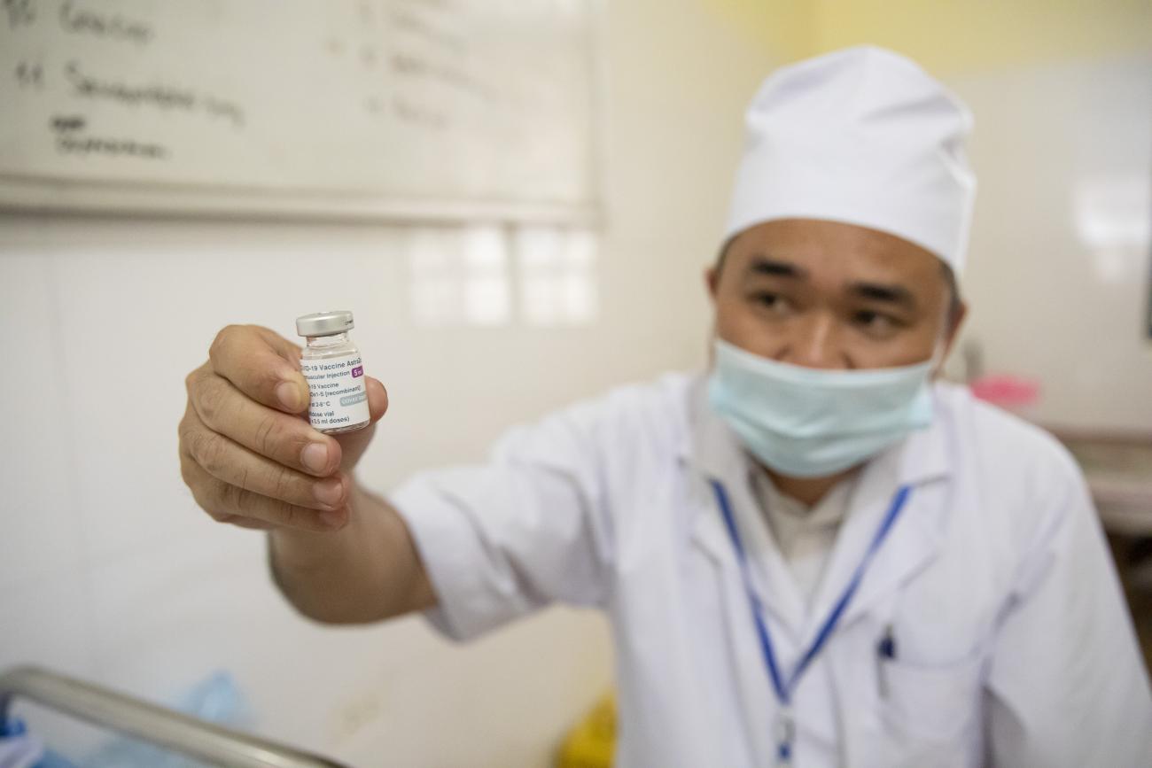 Медработник из округеа Лук Нам провинции Бак Гианг держит перед камерой ампулу с вакциной