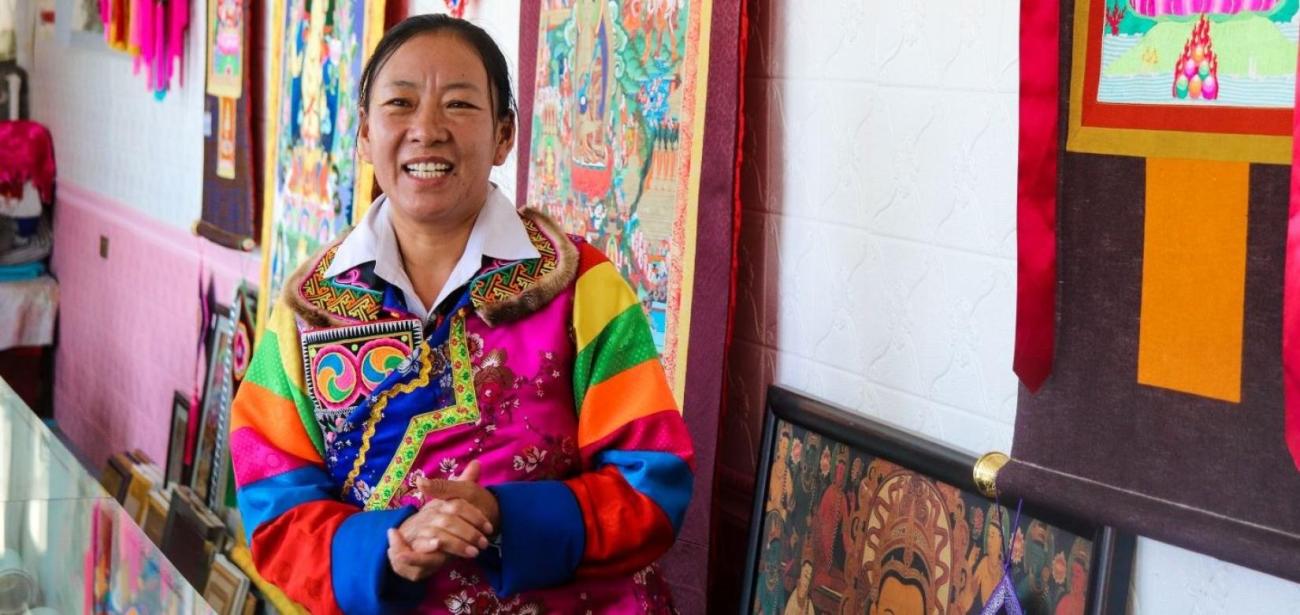 A smiling woman in thangka embroidery