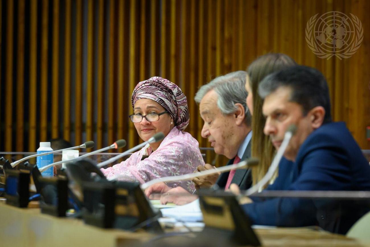 Une femme vêtue d'un châle et d'un foulard de couleur claire s’exprime dans un micro, aux côtés de deux hommes, en tournant la tête vers la caméra, lors d’une conférence organisée par l’ONU.