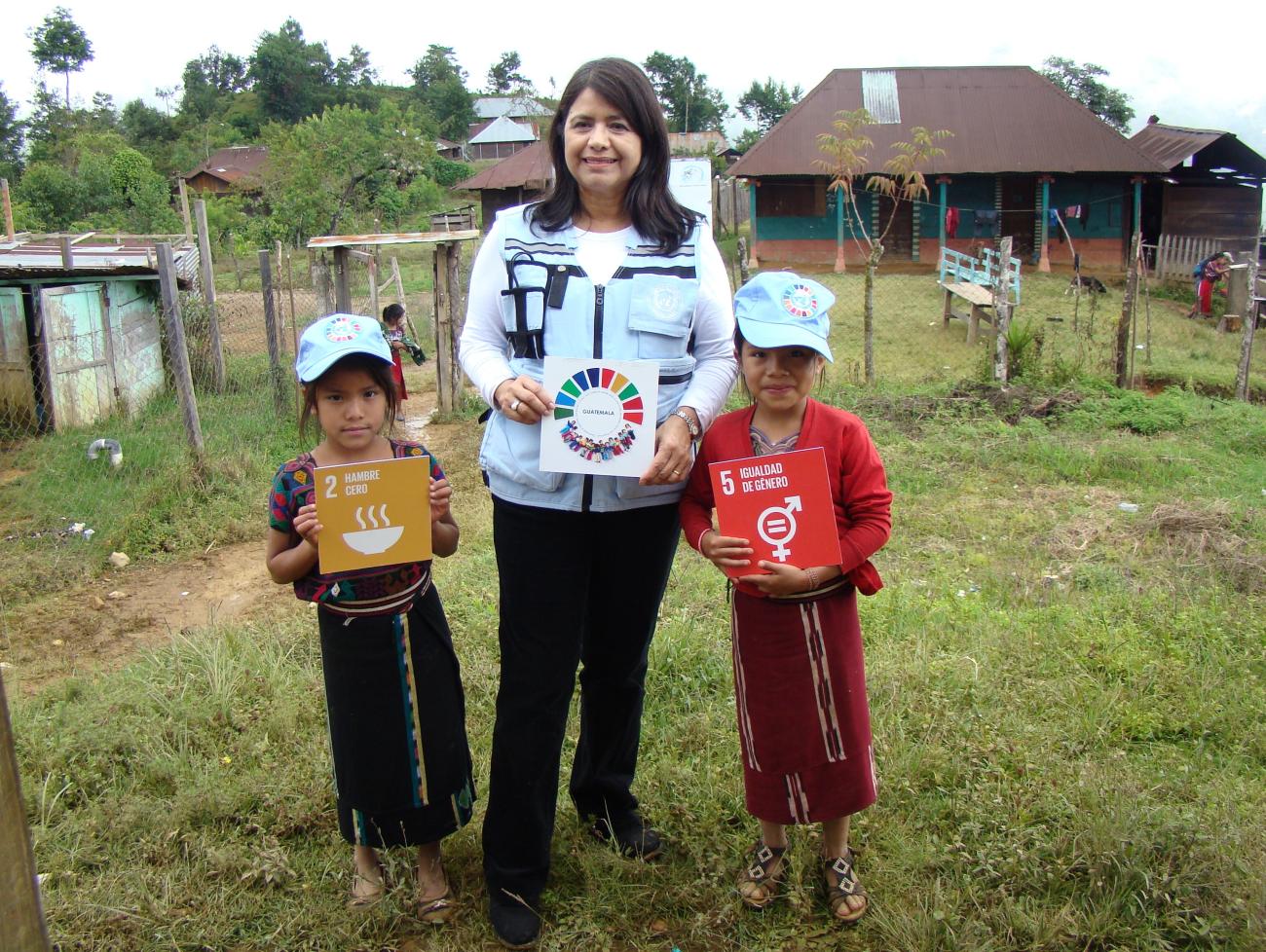 Resident Coordinator in Guatemala, Rebeca Arias Flores, promoting the Sustainable Development Goals with the help of two young children in Nebaj, Quiché, during a burial ceremony.