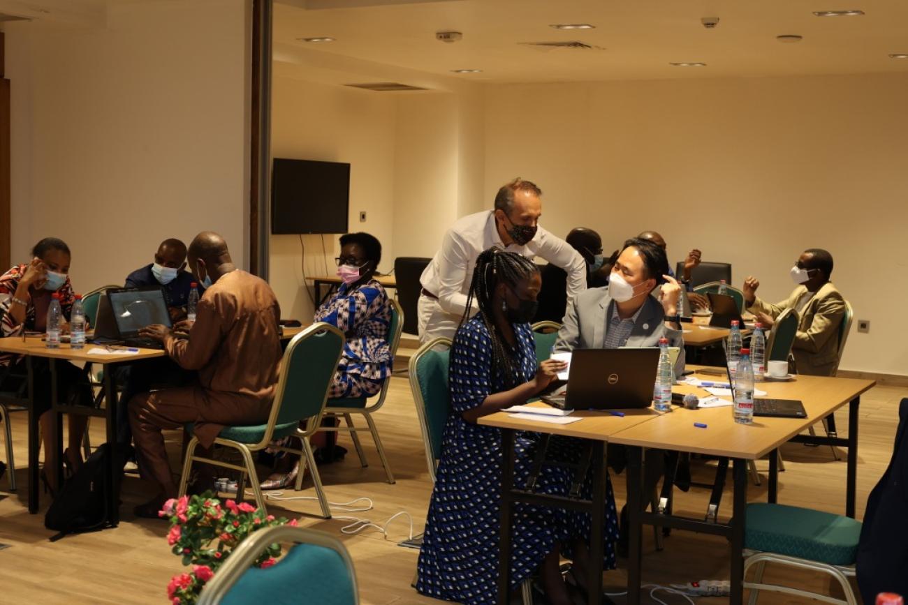 Groups of 4 people sit behind computers, dotted around a room, in what appears to be a hands-on training session.