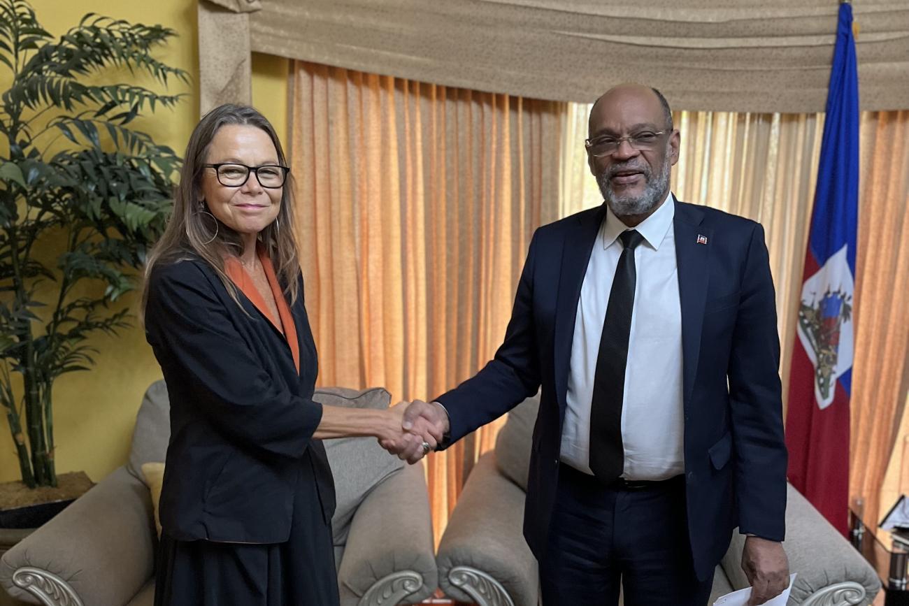Ulrika Richardson, new UN Deputy Special Representative in Haiti, and the Haitian Prime Minister, Ariel Henry, shake hands in an office with the Haitian flag in the background.