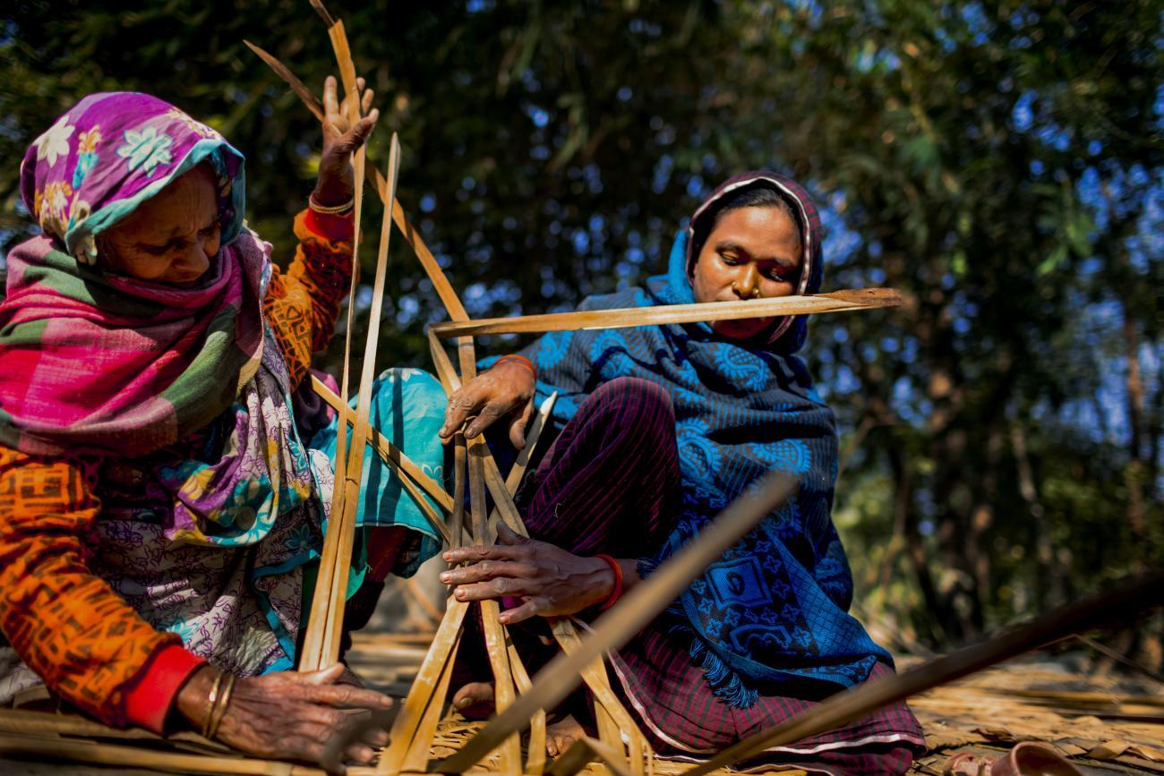 نساء يرتدين أوشحة ملونة يعملن بالخشب في بنغلاديش.