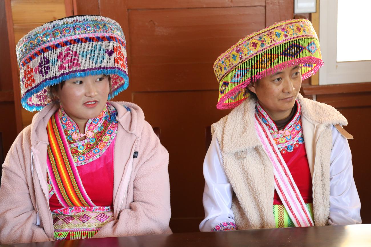 Deux femmes chinoises issues d'un groupe ethnique minoritaire en Chine portent des vêtements traditionnels de couleurs vives et des couvre-chefs traditionnels.