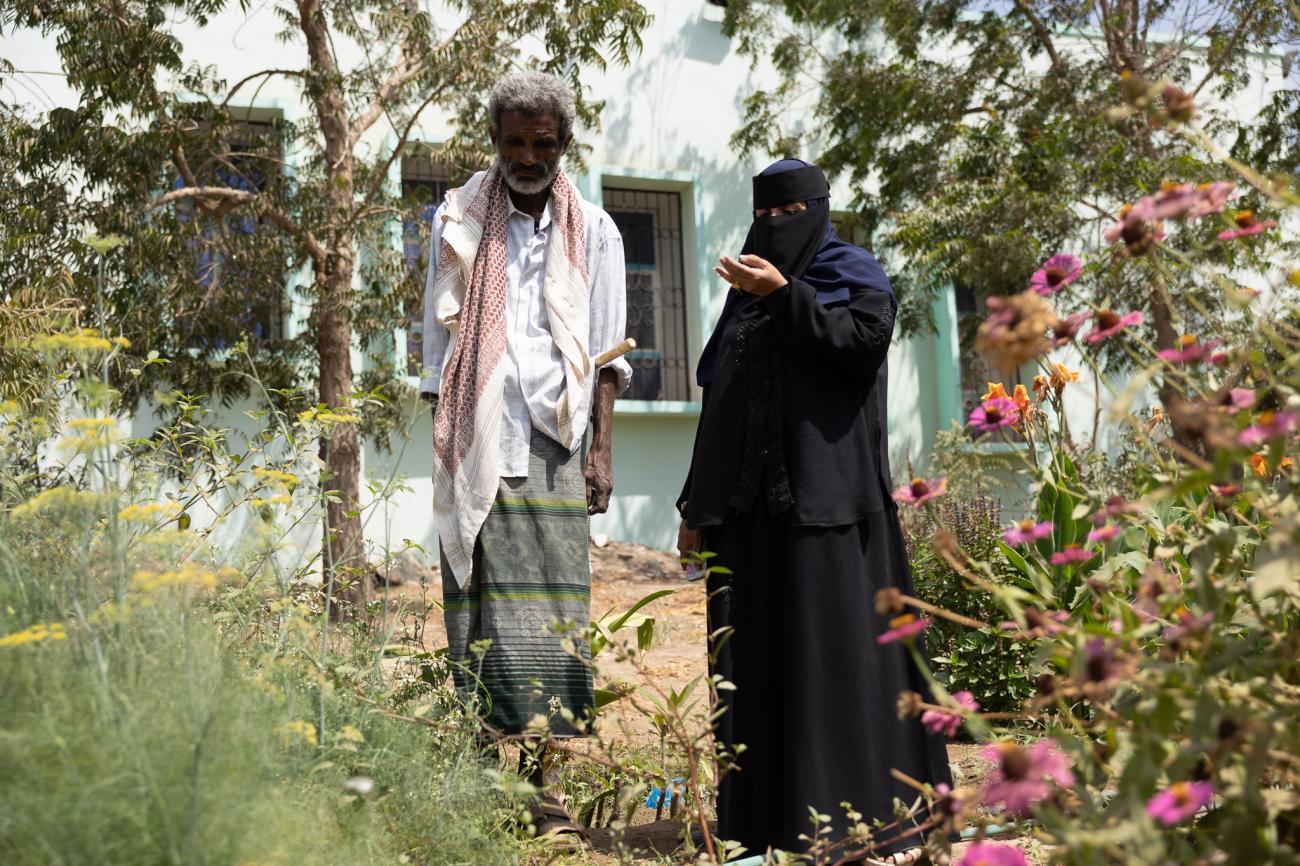 一个男人和一个戴着面纱的女人在一个小花园里。