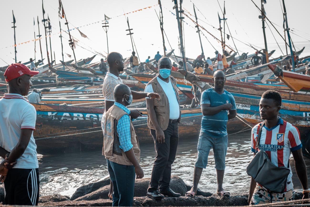 Le Coordonnateur résident des Nations Unies en Sierra Leone discute de l'ODD 13 avec des propriétaires de bateaux à Tombo, une localité côtière de pêcheurs située non loin de Freetown, la capitale de la Sierra Leone.