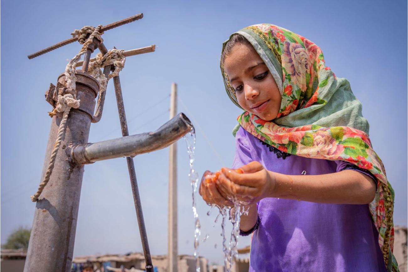 Young girl catching water from a pipe in Pakistan