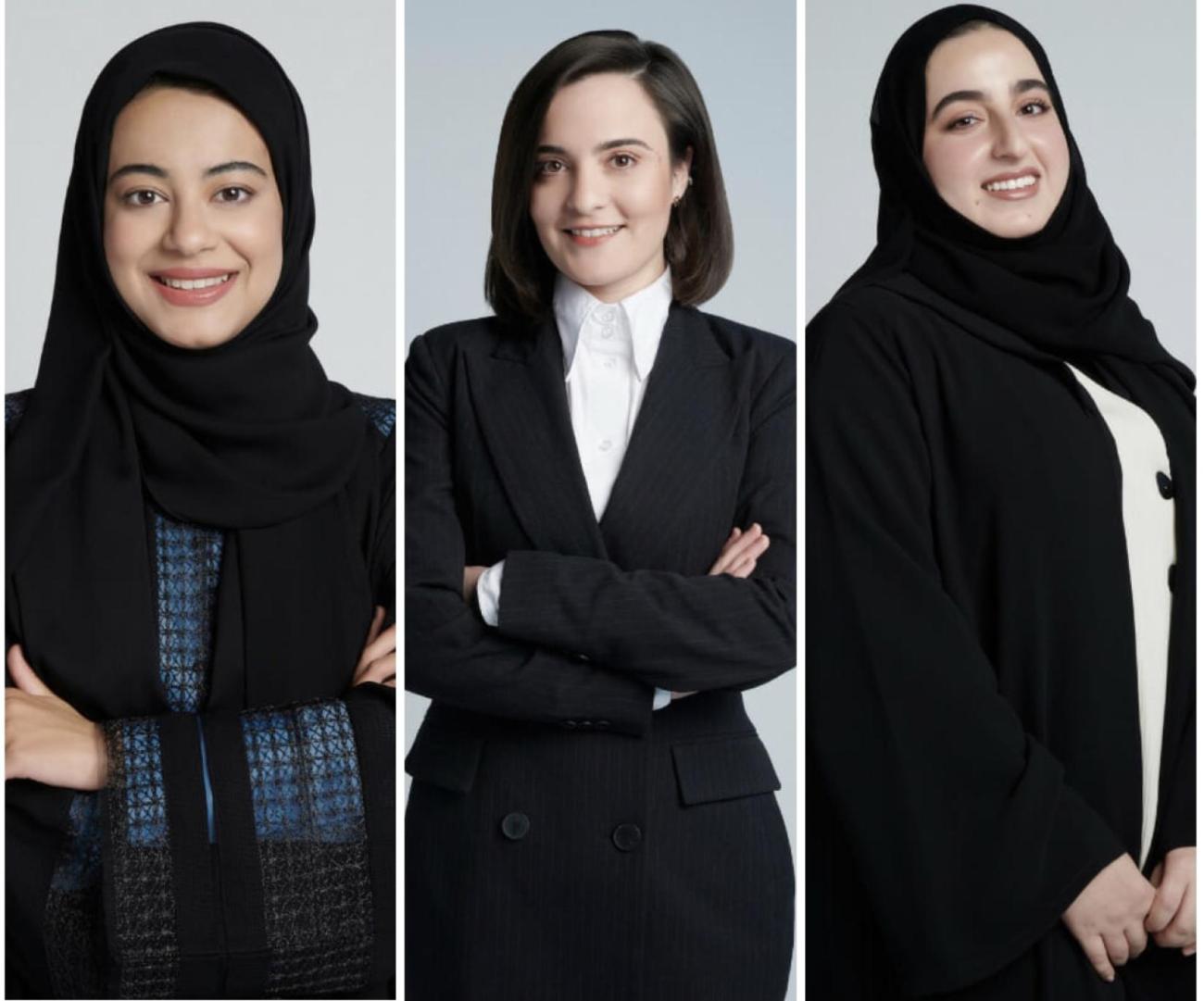 Three women in black clothes, two of them in headscarves smiling at the camera, side by side