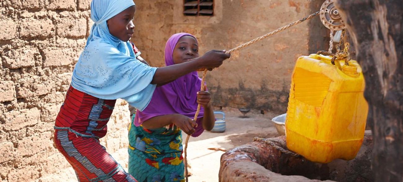Des filles vont chercher de l'eau dans un puits devant leur maison à Dedougou, au Burkina Faso.