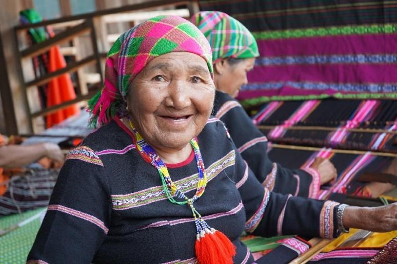 Woman in a colourful traditional dress and headscarf smiling at the camera