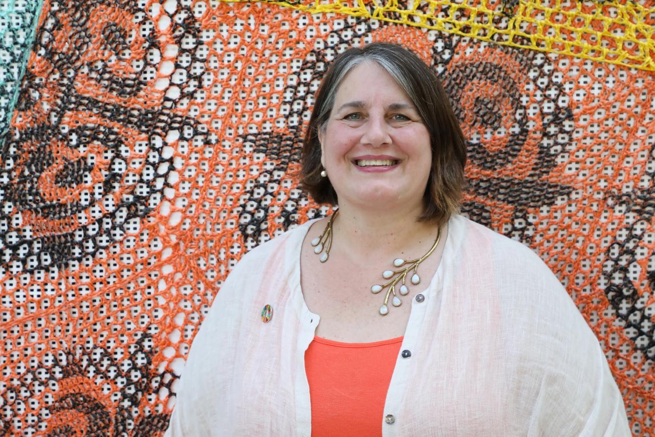 Woman in a white and orange shirt against a colourful printed background
