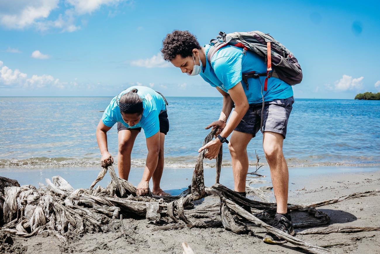 Two volunteers in blue t-shirts clean up parts of a beach