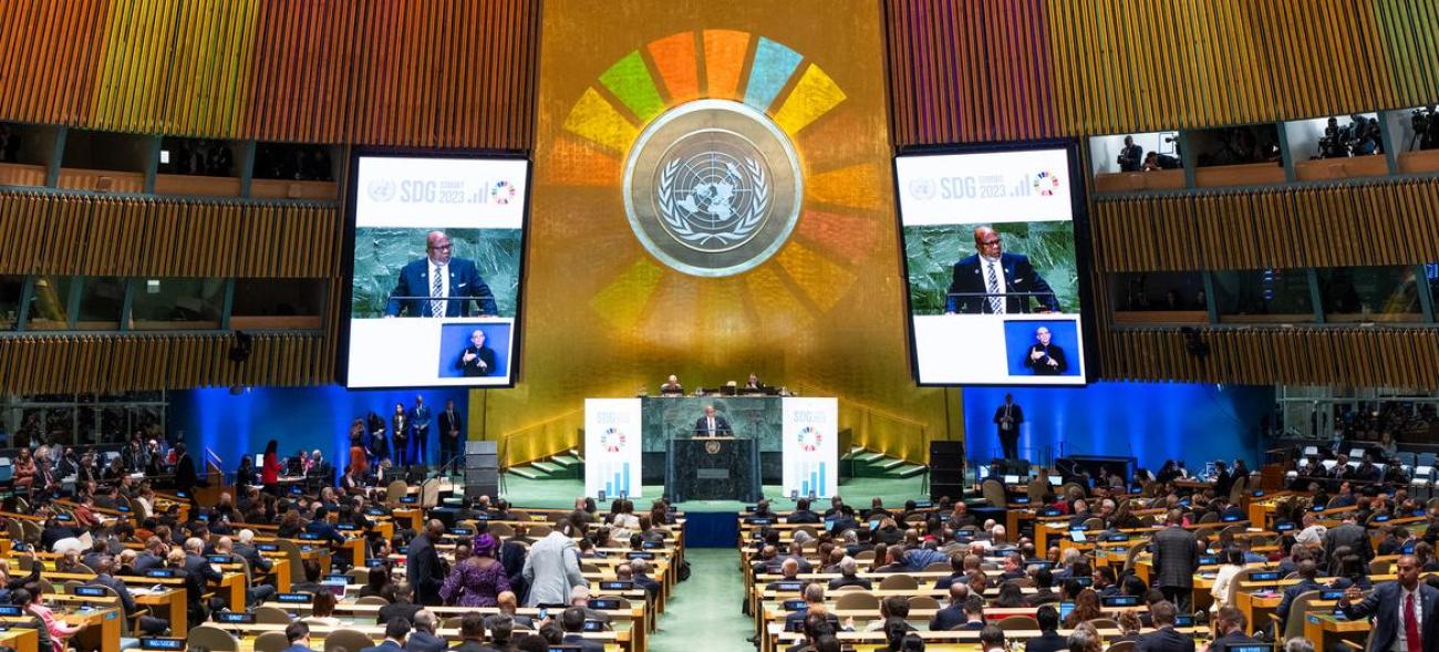 A shot of the general assembly hall lit up with a projection of the SDGs at the 2023 Summit