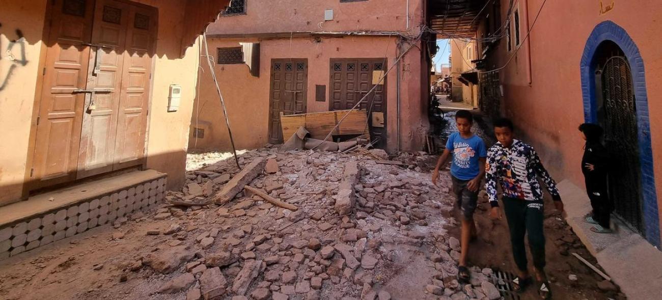 Two young people walk through a crumbled building after the earthquake in Morocco