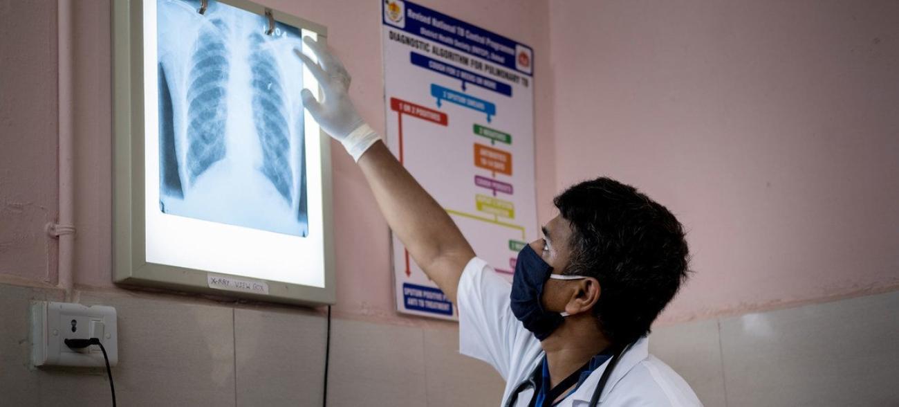 Мужчина в медицинской маске изучает рентгеновский снимок груди