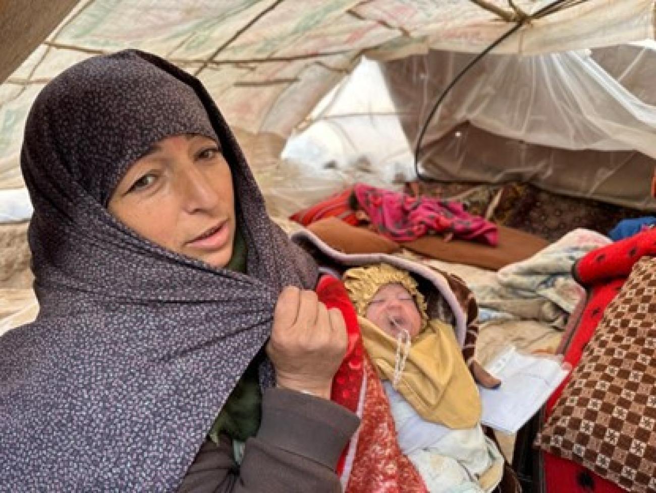 一名女性怀抱婴儿在地震后的救援帐篷里