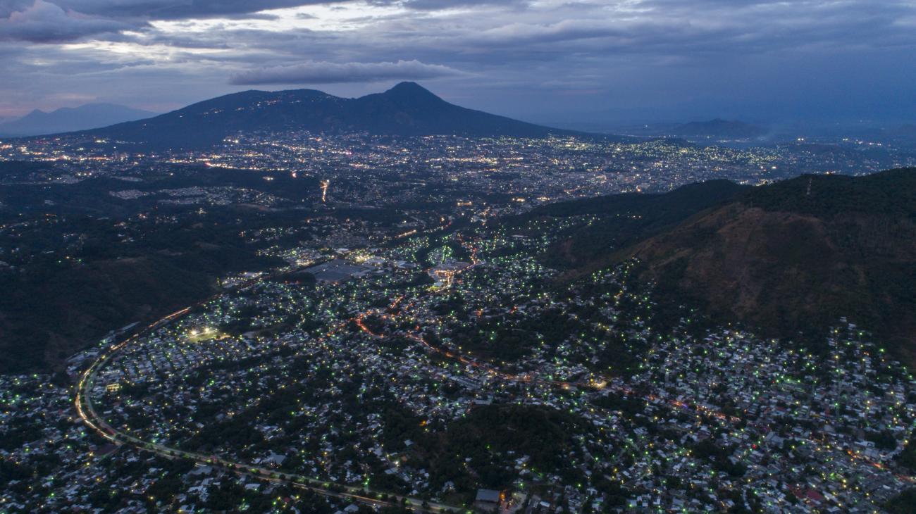 An aerial shot of El Salvador, with mountains in the distance and houses on the ground.