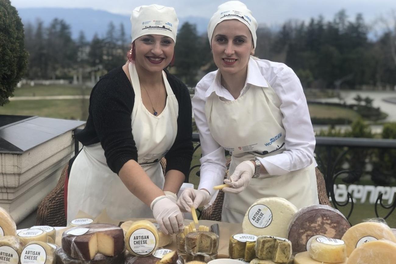 Two women selling cheese in an outdoor setting