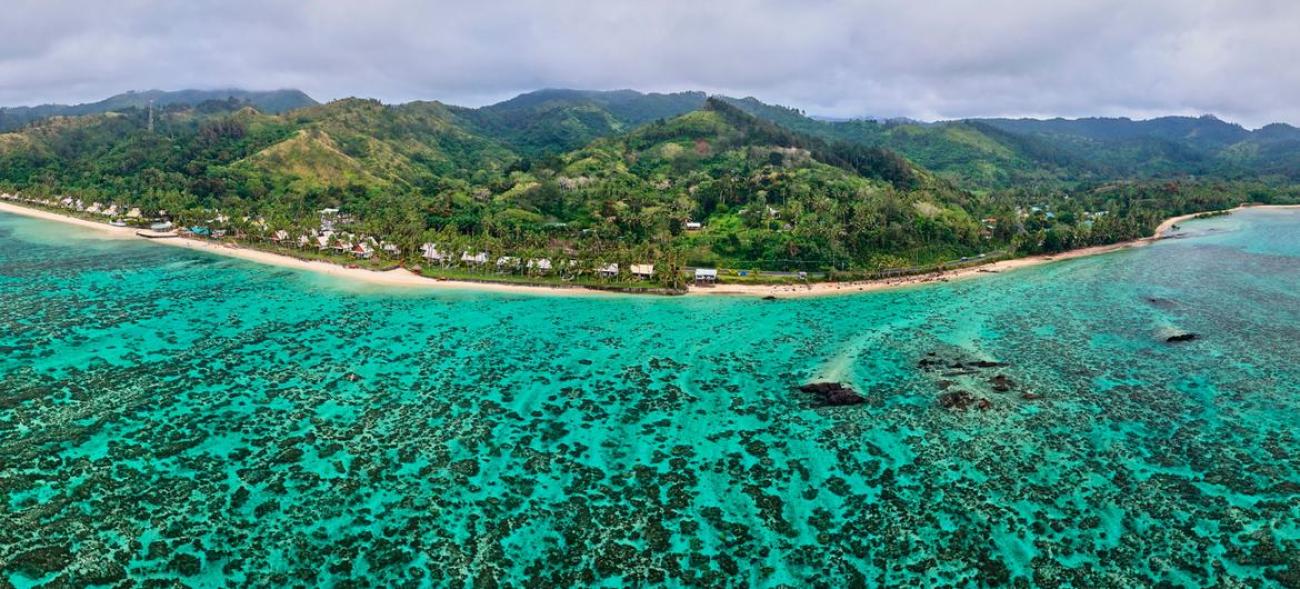 Зеленый берег острова Фиджи с зелоно-голубой прозрачной водой моря