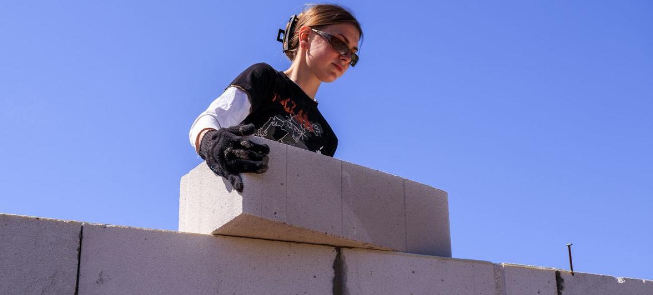 Молодая женщина в солнечных очках на стройке двигает бетонный блок