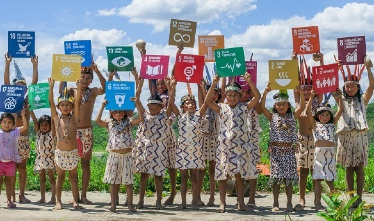 Muchos niños y niñas sostienen en alto los Objetivos de Desarrollo Sostenible.