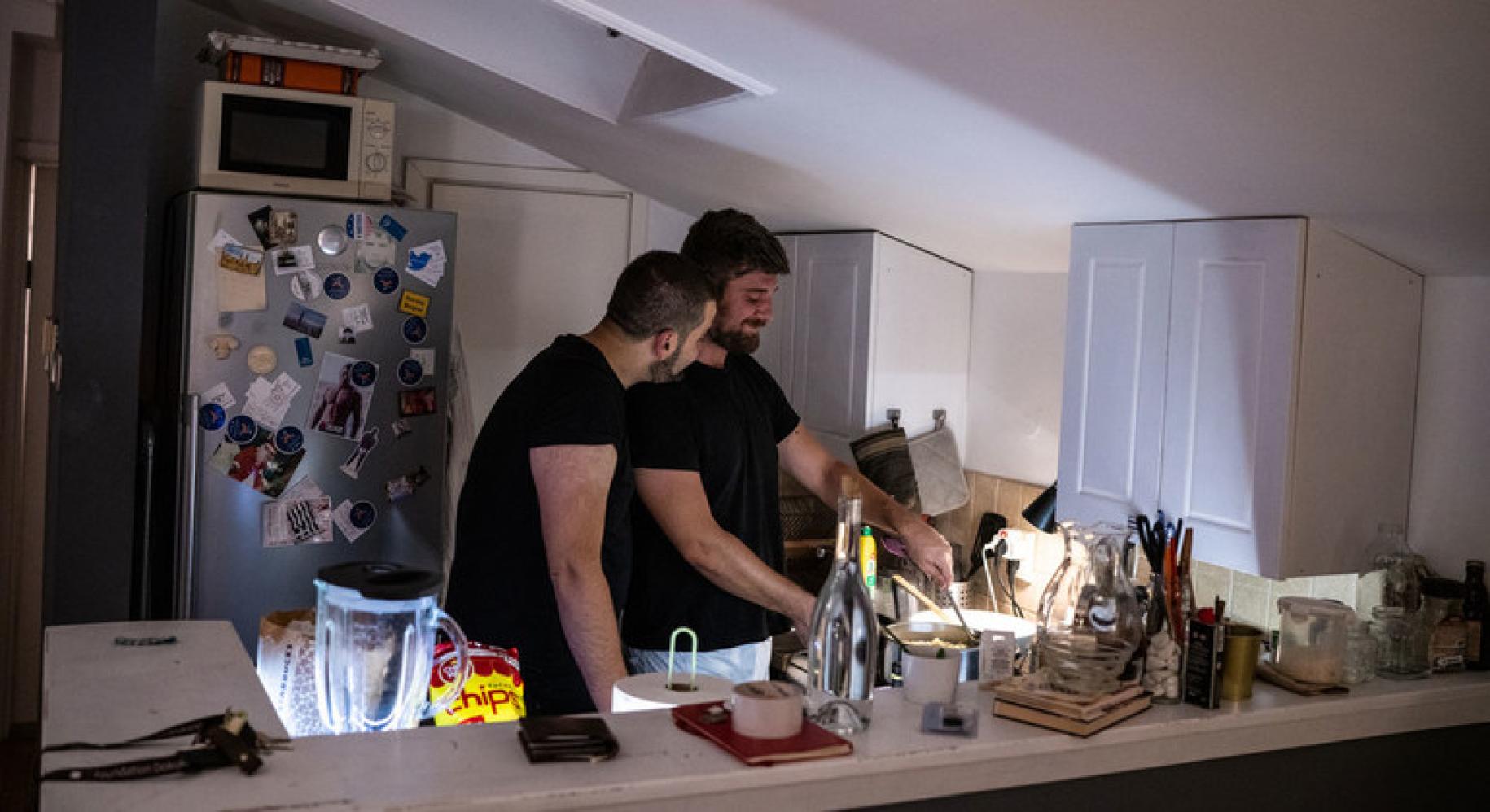 Two men are pictured in their kitchen preparing a meal together