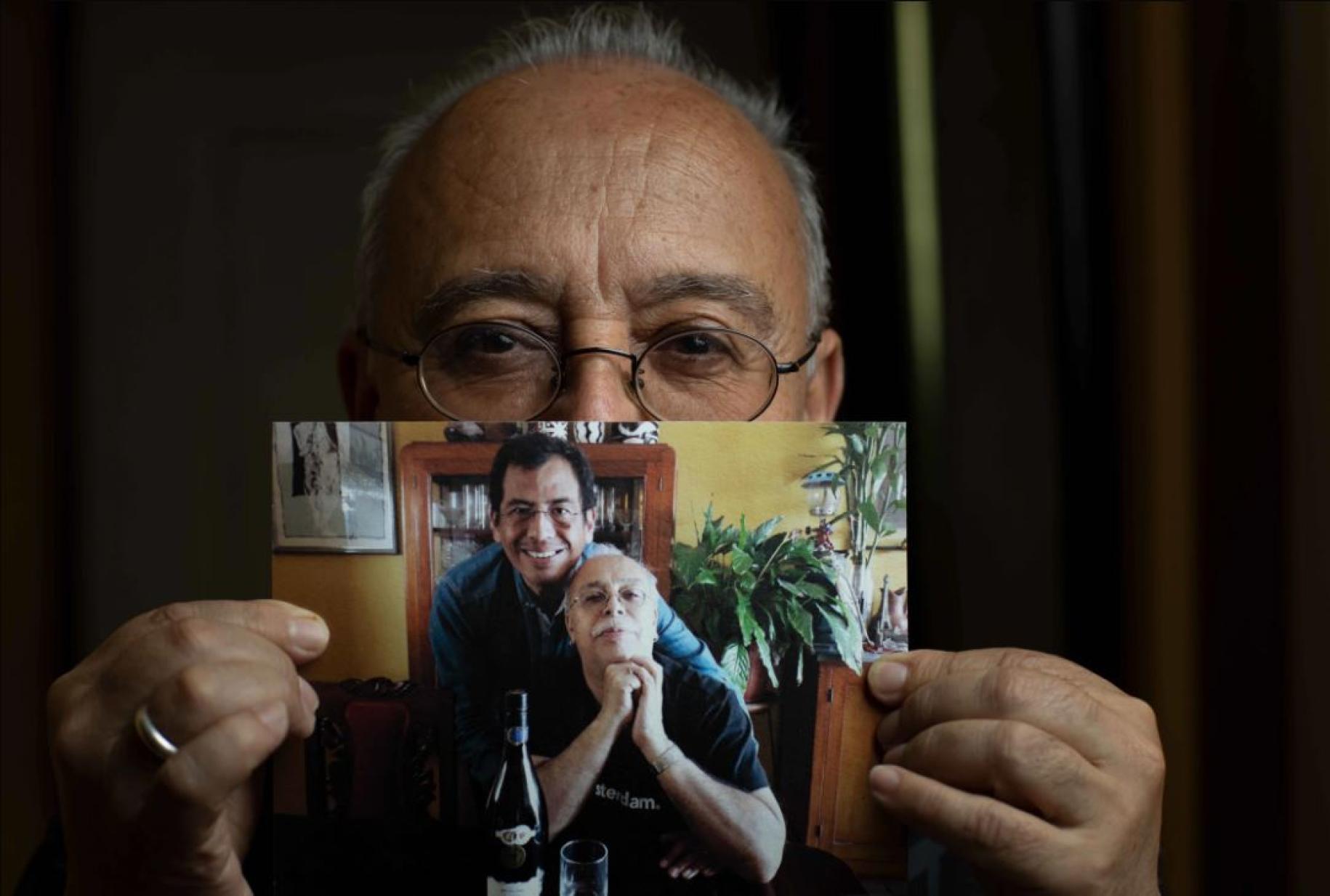 Manolo holds a photograph showing himself and his partner Martín. 