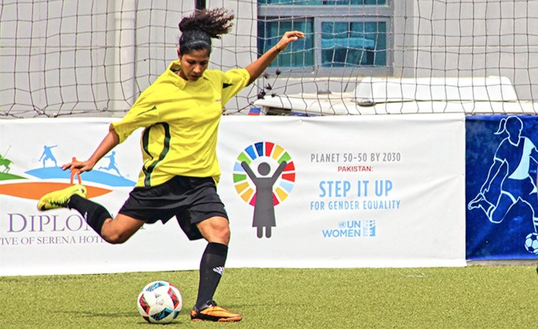 Se muestra a Hajra Khan, capitana del equipo nacional femenino de fútbol de Pakistán, pateando una pelota de fútbol durante un juego.