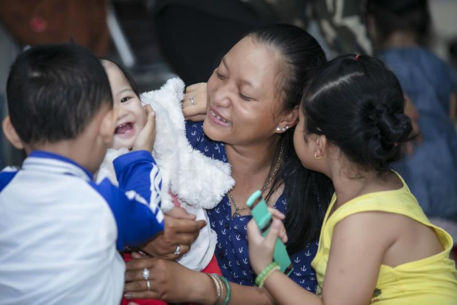 تشاو باو تحمل طفلًا رضيعًا وإلى جانبها صبي وفتاة.