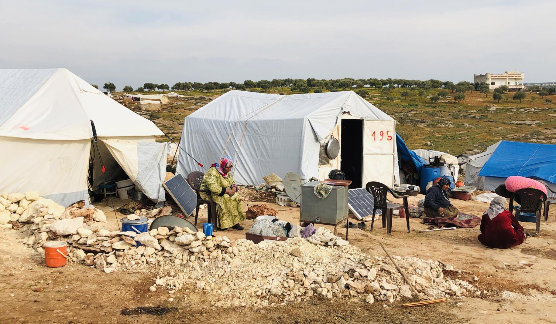 Los desplazados se sientan fuera de sus tiendas de campaña en el campamento de desplazados internos de Harbonosh.