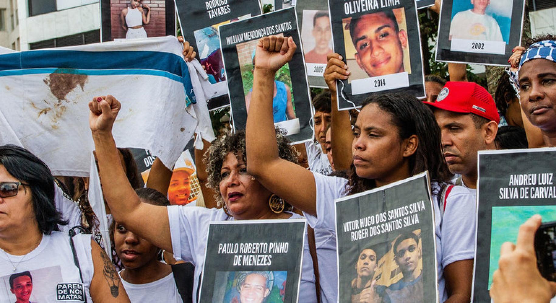 La imagen muestra a un grupo de hombres y mujeres que sostienen carteles con imágenes de jóvenes que han fallecido.