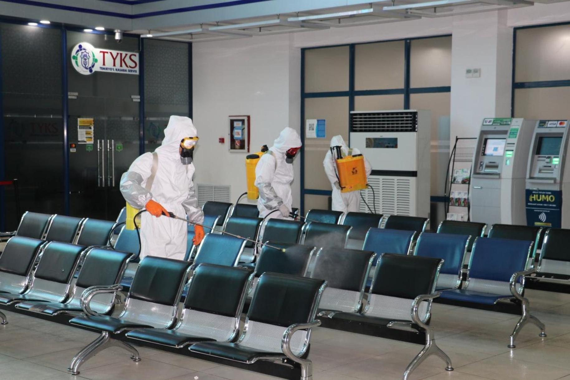 People wearing head-to-toe protective gear are shown cleaning and sanitizing a waiting area.