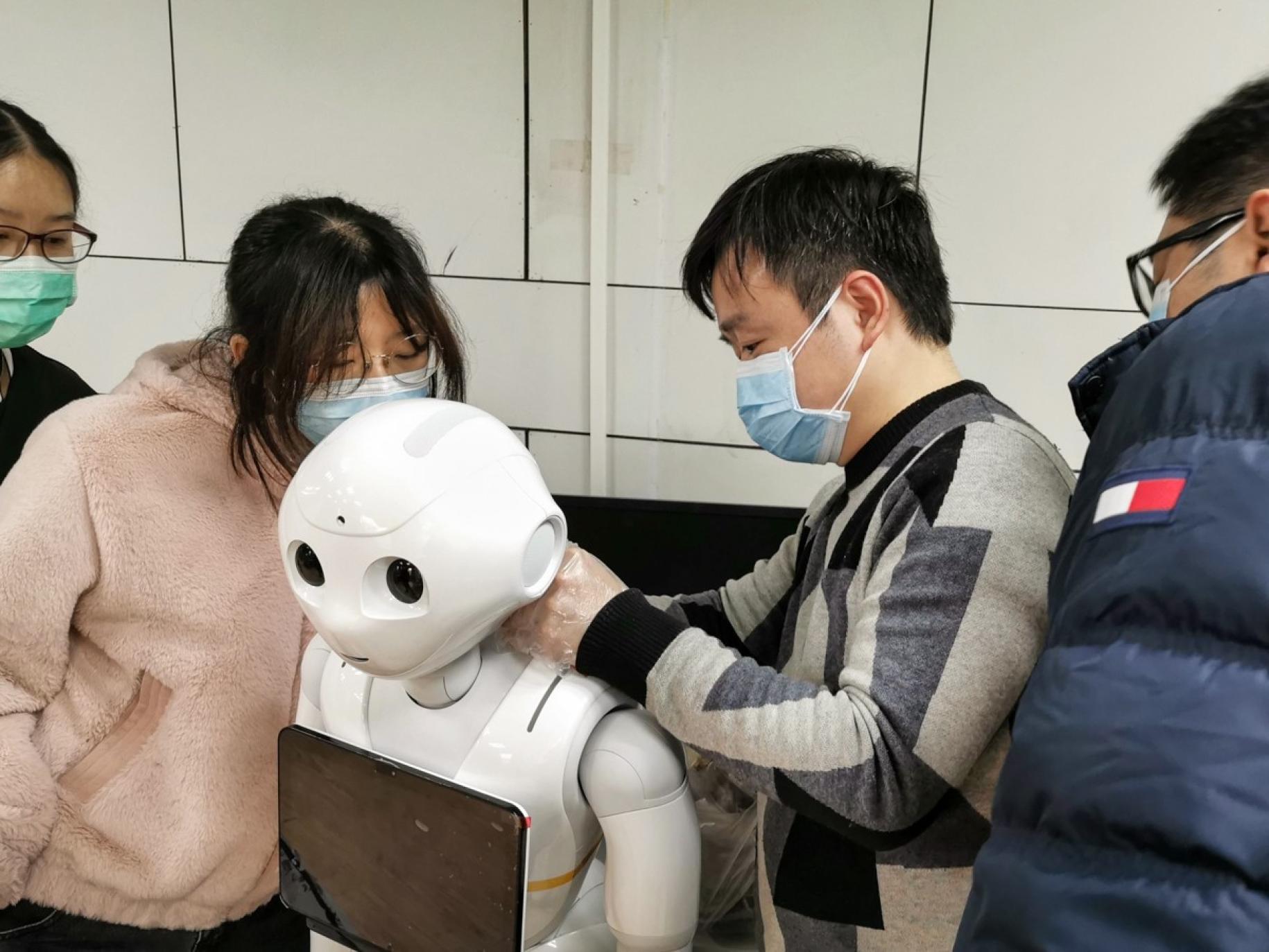 Muestra a jóvenes manejando un robot. Los robots se utilizan en muchos hospitales para entregar alimentos, medicamentos y otros suministros; para desinfectar hospitales y otras áreas públicas para controlar la temperatura de los pacientes y responder preguntas comunes.
