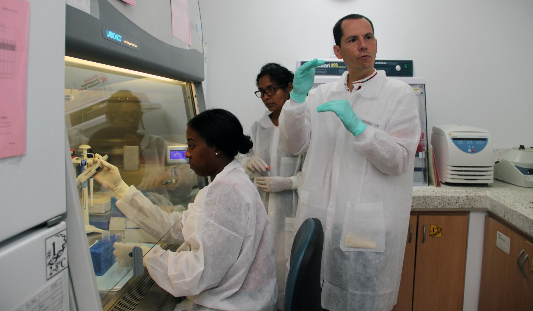 ثلاثة أشخاص في مختبر يرتدون الملابس الواقية.